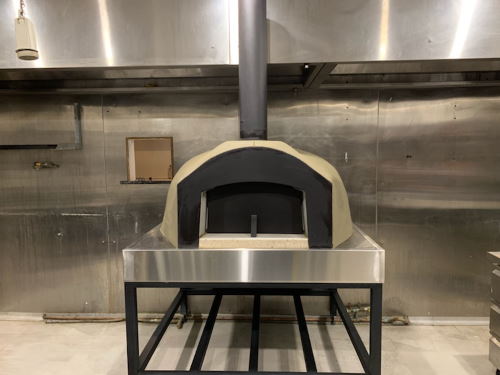 A small commercial grade wood fired oven mounted on a metal frame